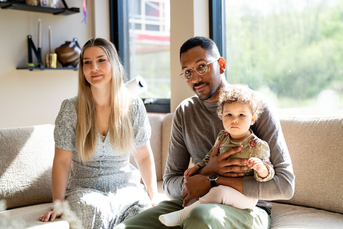 Familie med baby sitter i sofaen