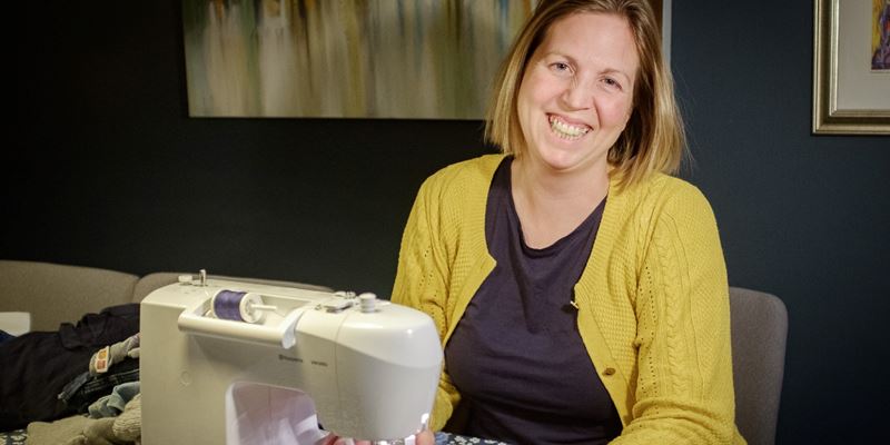 Vibeke Faye Wevle sitter ved symaskinen og lapper barneklær