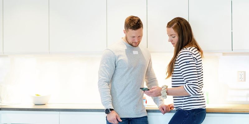 Par står på kjøkkenet og ser på mobilen