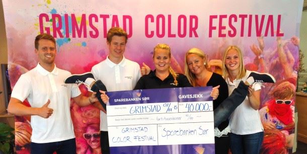 Ansatte i Sparebanken Sør deler ut gavesjekk til Grimstad Color Festival