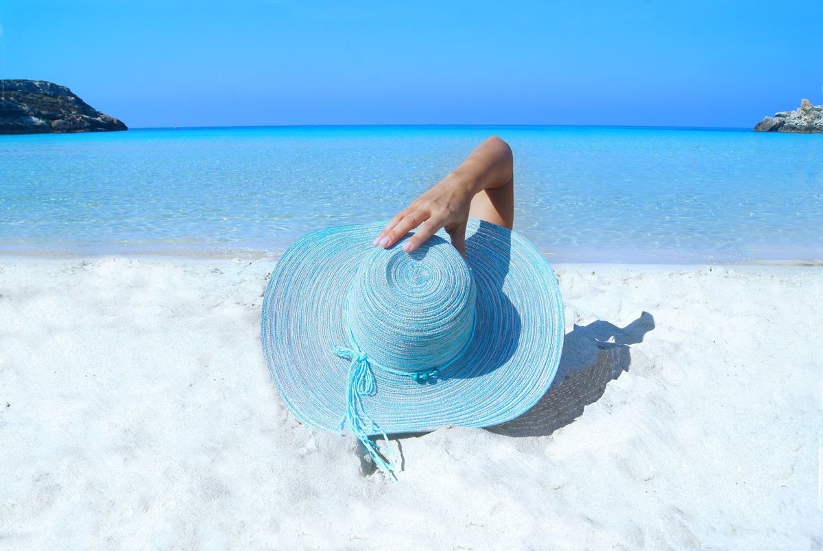 Dame med solhatt på strandferie
